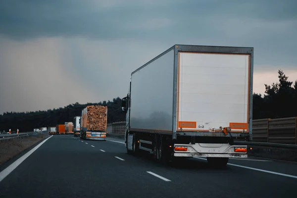 Modern semi-trailer trucks on the highway driving in the right lane. Commercial vehicle for shipping and post delivery. Shipping of the goods on land door-to-door