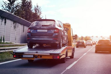 Çekicinin yan görüntüsü ve servis dışı bir araç. Acil durum yol yardımı. Motor sorunlarını ve çözümlerini kontrol et.