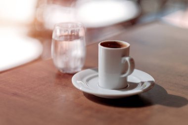 Beyaz bardakta espresso kahvesi. Mutlu sabahlar kavramına asgari bir yaklaşım. Sabah rutini. Arka planda bir bardak su olan bir fincanda Americano espresso..