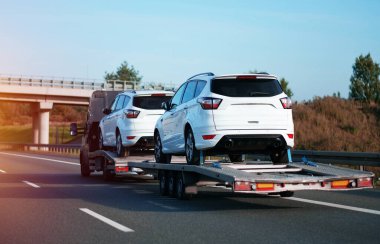 Gıcır gıcır beyaz SUV 'un güvenli bir şekilde nakledilmesi Ağır Taşıyıcı Taşıyıcı' nın yardımıyla otoyolda görüldü.