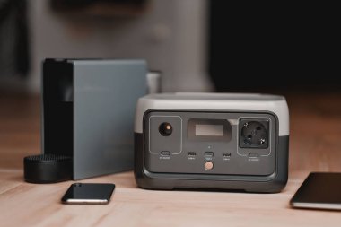 Kahve makinesi ve portatif elektrik santrali ahşap bir zeminde. Telefonları, dizüstü bilgisayarları ve mutfak aletlerini şarj etmek için mobil cihaz. Ev için sistem çözümünü yedekle.