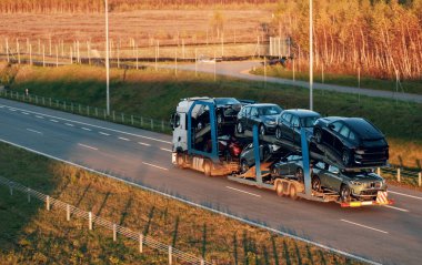 Satılık yepyeni SUV arabaları olan bir karavan kamyonu. Yeni araba teslimatı ve nakliyat. Araba taşıyıcı karavanı müşteriler için bir sürü yeni arabayla dolu. İki seviye modüler hidrolik yarı römork