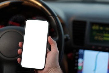Sürücü koltuğunda elinde akıllı telefonun maketini tutan bir adam. Eldeki dokunmatik ekranın boş görüntüsü