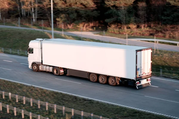 stock image Modern white semi-trailer trucks on the highway driving in the right lane. Commercial vehicle for shipping and post delivery. Shipping of the goods on land with a door-to-door delivery process.