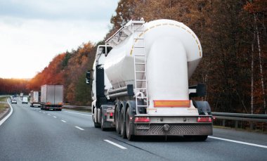 Petrol kargo kamyonu otobanda petrol nakliyesi yapıyor. Yakıt teslimatı. Havacılık yakıtı taşımacılığı. Bir otoyolda sıkıştırılmış gaz kamyonu dikiz aynası. Süt ürünleri taşıyıcısı