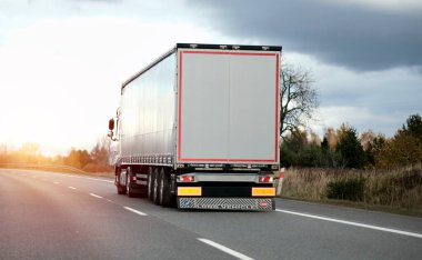 Otoyolda sağ şeritten giden modern beyaz yarı karavan kamyonları. Nakliye ve posta teslimatı için ticari araç. Malların kapı kapı teslimatı ile birlikte karada nakliyesi..