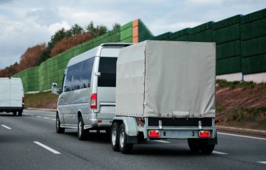 Kişisel eşyaları ve yolcuların personeliyle dolu kısa bir karavanı olan bir yolcu otobüsü. Otoyolda küçük ölçekli yolcu otobüsü hareket halinde..