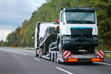 Çekicinin yan görüntüsü ve kargo nakliyesi için yepyeni ticari bir araç. Acil durum yol yardımı. Yoldaki Araç Mekanik Sorunu. Garanti davası. Yükleme Beyannamesi.