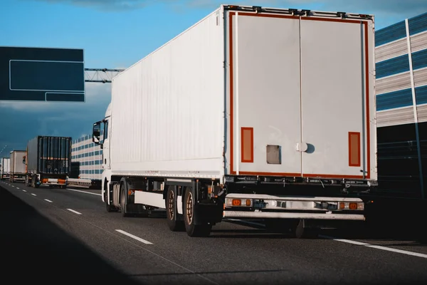 stock image Modern white semi-trailer trucks on the highway driving in the right lane. Commercial vehicle for shipping and post delivery. Shipping of the goods on land door-to-door