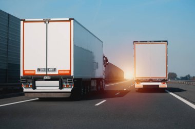 Otobanda birbirini sollayan ve sollayan iki modern yarı karavan kamyonu. Nakliye ve posta teslimatı için ticari araç. Malların kapı kapı dolaşımı.