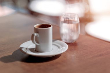 Beyaz bardakta espresso kahvesi. Mutlu sabahlar kavramına asgari bir yaklaşım. Sabah rutini. Arka planda bir bardak su olan bir fincanda Americano espresso..