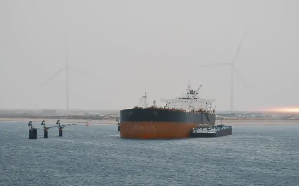 Oil Products Tanker Carrier In The International Port During Fuel Bunkering Supply Process. Ship-To-Ship Operation With The Wind Generators In The Background