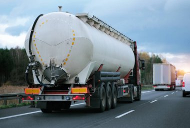 Otoyolda petrol kamyonu fosil petrol rafinerisi ürünleri taşıyor. Yakıt teslimatı. Havacılık yakıtı taşımacılığı. Bir otoyolda sıkıştırılmış gaz kamyonu dikiz aynası. Süt ürünleri taşıyıcısı