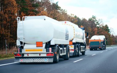 Otoyolda petrol kamyonu fosil petrol rafinerisi ürünleri taşıyor. Yakıt teslimatı. Havacılık yakıtı taşımacılığı. Bir otoyolda sıkıştırılmış gaz kamyonu dikiz aynası. Süt ürünleri taşıyıcısı