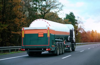 Otoyolda petrol kamyonu fosil petrol rafinerisi ürünleri taşıyor. Yakıt teslimatı. Havacılık yakıtı taşımacılığı. Bir otoyolda sıkıştırılmış gaz kamyonu dikiz aynası. Süt ürünleri taşıyıcısı