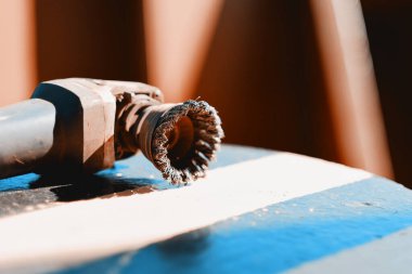 Yük gemisinin güvertesinde metal bir bardak fırçasıyla öğütücü kullanarak koruyucu bakım. 