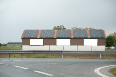 Warehouse with solar panels on the roof. Nature-produced energy. clipart