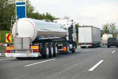 Otoyolda petrol kamyonu fosil petrol rafinerisi ürünleri taşıyor. Yakıt teslimatı. Havacılık yakıtı taşımacılığı. Bir otoyolda sıkıştırılmış gaz kamyonu dikiz aynası. Süt ürünleri taşıyıcısı.