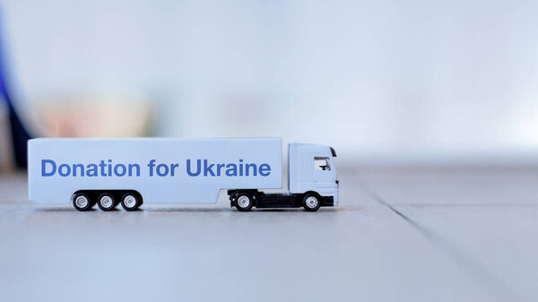 Пожертвование для Украины Подпись на прицепе грузовика с белой игрушкой, отображается на гладкой поверхности