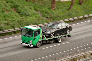 Flatbed üzerinde siyah Alman yaşlandırılmış sedanı olan tek asansörlü çekici.