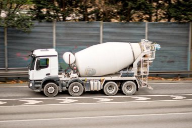 Truck With Rotating Circulating Concrete Mixer On The Way To The Construction Building Project On Empty Highway In The Right Lane clipart