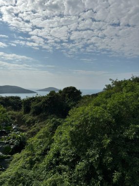 Doğayı, denizi, adaları ve arkasında beyaz bulutlar olan mavi gökyüzünü görüntüle 