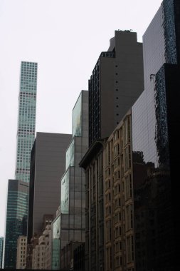 Bulutlu bir günde Manhattan 'ın yerleşim yerinin tepeden görünen görüntüsü, parlak beyaz gökyüzü altında eski tuğla binalar ve modern cam apartmanlar arasındaki zıtlığı gözler önüne seriyor.