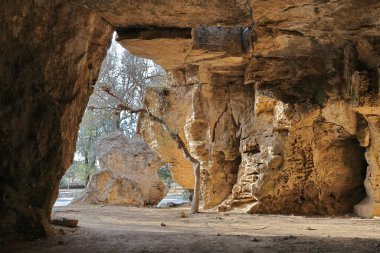 Kıbrıs Rum Kesimi 'nin Paphos kentindeki antik yeraltı mezarlarının iç görünümü, sert kaya oluşumları ve açıklıklardan süzülen doğal ışığı gösteriyor..  