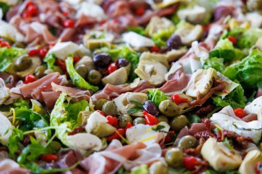 İçinde salata, marul, zeytin ve jambon gibi çeşitli malzemeler olan bir salata. Salata tabağa serildi ve servis edilmeye hazır.