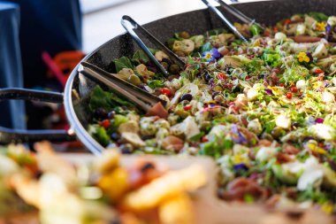 Bir büyük kase salata, çeşitli sebzeler ve birkaç parça pastırma. Salata büyük bir tavada servis edilir ve diğer yiyeceklerle çevrilidir.