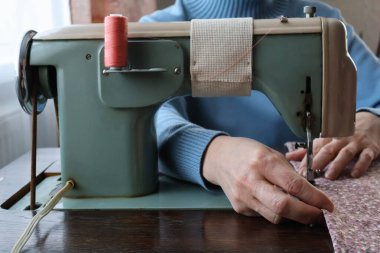 Bir kadın dikiş makinesine dikiş dikiyor..