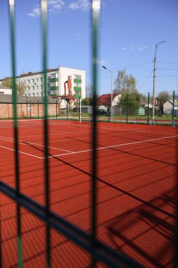 Okul bahçesindeki çitlerin arkasında bir tenis kortu..