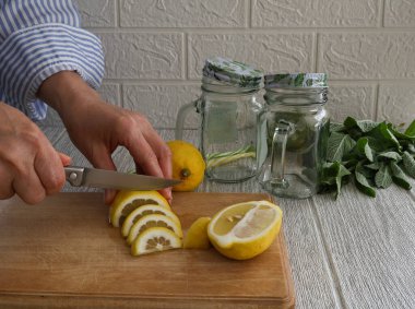 Bir kadın içki yapmak için limonu dilimlere ayırır.
