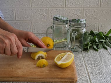 Bir kadın nane kokteyli için limon dilimliyor..