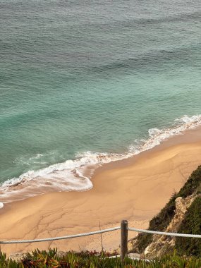 Portekiz 'de kumlu sahil ve çitli okyanus manzarası
