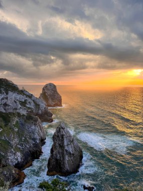 Orange Sky Over Atlantic Cliffs, Portekiz Açıklaması: Portekiz 'deki Cape Roca Burnu' nda günbatımında okyanus manzaralı ve sivri kayalıklı yüksek uçurum kenarı. Görkemli ve güçlü doğal manzara..