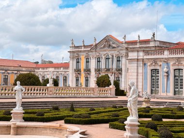 Queluz Sarayı manzarası, ön planda, Portekiz 'deki açık güneşli gökyüzünün altında ayrıntılı bir taş heykel var..
