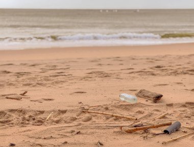  Plastik şişe ve dağınık çöp güçlü bir fırtınadan sonra kumlu bir plajda yatıyor..