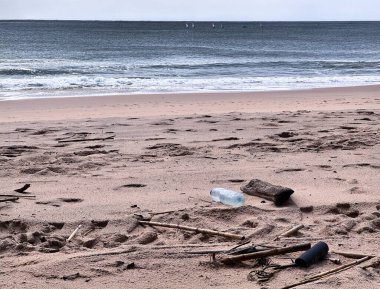  Plastik şişe ve dağınık çöp güçlü bir fırtınadan sonra kumlu bir plajda yatıyor..