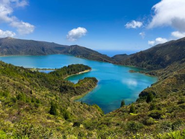 Turkuaz su, yeşil yamaçlar ve Azores 'teki açık gökyüzü ile Lagoa do Fogo' nun göz kamaştırıcı panoramik görüntüsü.