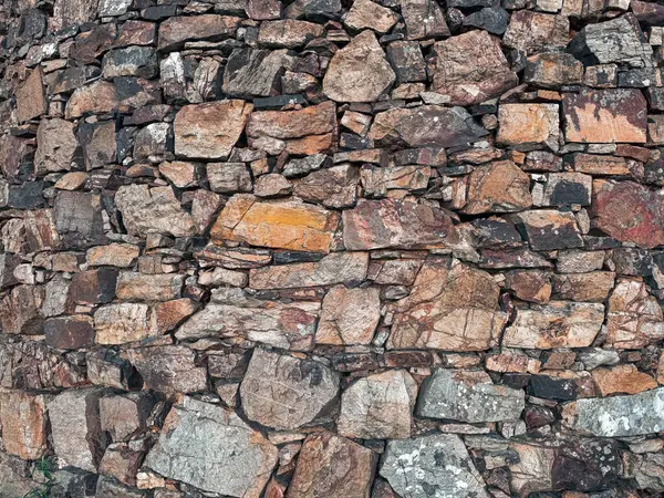 Zamanla yaşlanan taş bir duvarın yüzeyi. Topraksı, sessiz renklerle kaotik taş yerleştirme