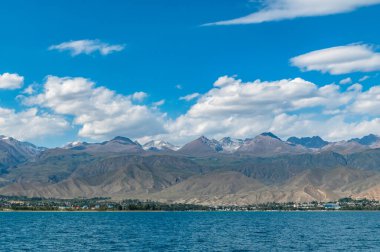 Kırgızistan 'daki dağ gölü Issyk-Kul, Cholpon-Ata şehri ve dağ sıraları manzarası