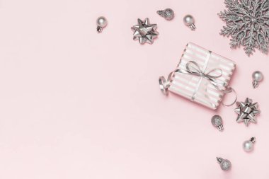 Yılbaşı kartı, geçmiş. Üzerinde gümüş kurdeleler ve pembe arka planda Noel topları olan pembe hediye kutusu. Pembe Noel. Metin için yer.