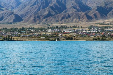Kırgızistan 'daki Dağ Gölü Issyk-Kul, Cholpon-Ata şehrinin setinde beyaz yelkenli..