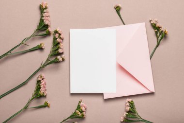 Pembe zarf ve kahverengi arkaplanda çiçekler olan boş form. Tebrik kartı, model..