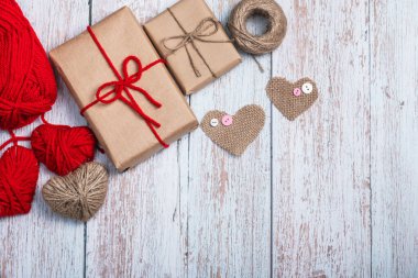İki hediye kutusu, çuval bezi, kırmızı iplik ve iplikten yapılmış kalpler, ahşap arka planda bir sicim topu. Hediyeler. Boşluğu kopyala.