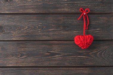 Kırmızı yün ipliklerden yapılmış ev yapımı kalp bir çiviye asılı. Sevgililer Günü konsepti. Hediye..