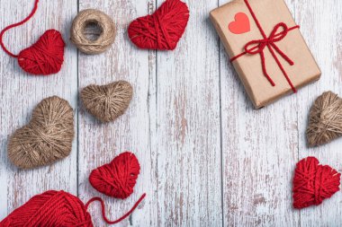 Hediye kutusu, sicim ve kırmızı yünden yapılmış kalpler kopya alanı olan ahşap bir arka planda. Sevgililer Günü konsepti.