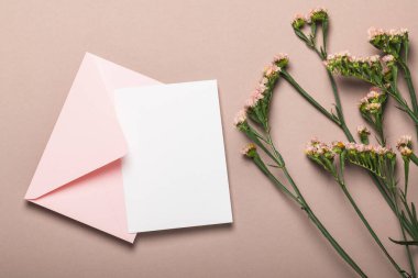 Pembe zarf ve kahverengi arkaplanda çiçekler olan boş form. Tebrik kartı, model..