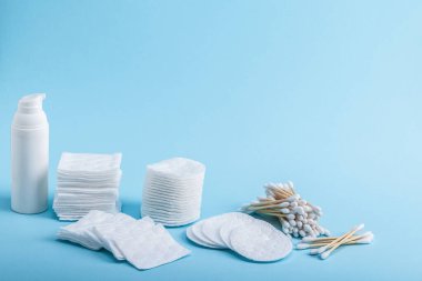 Bambu çevre dostu pamuklu çubuklar ve farklı şekillerde pamuk bezleri ve mavi arka planda krema veya özlü bir tüp. Boşluğu kopyala.